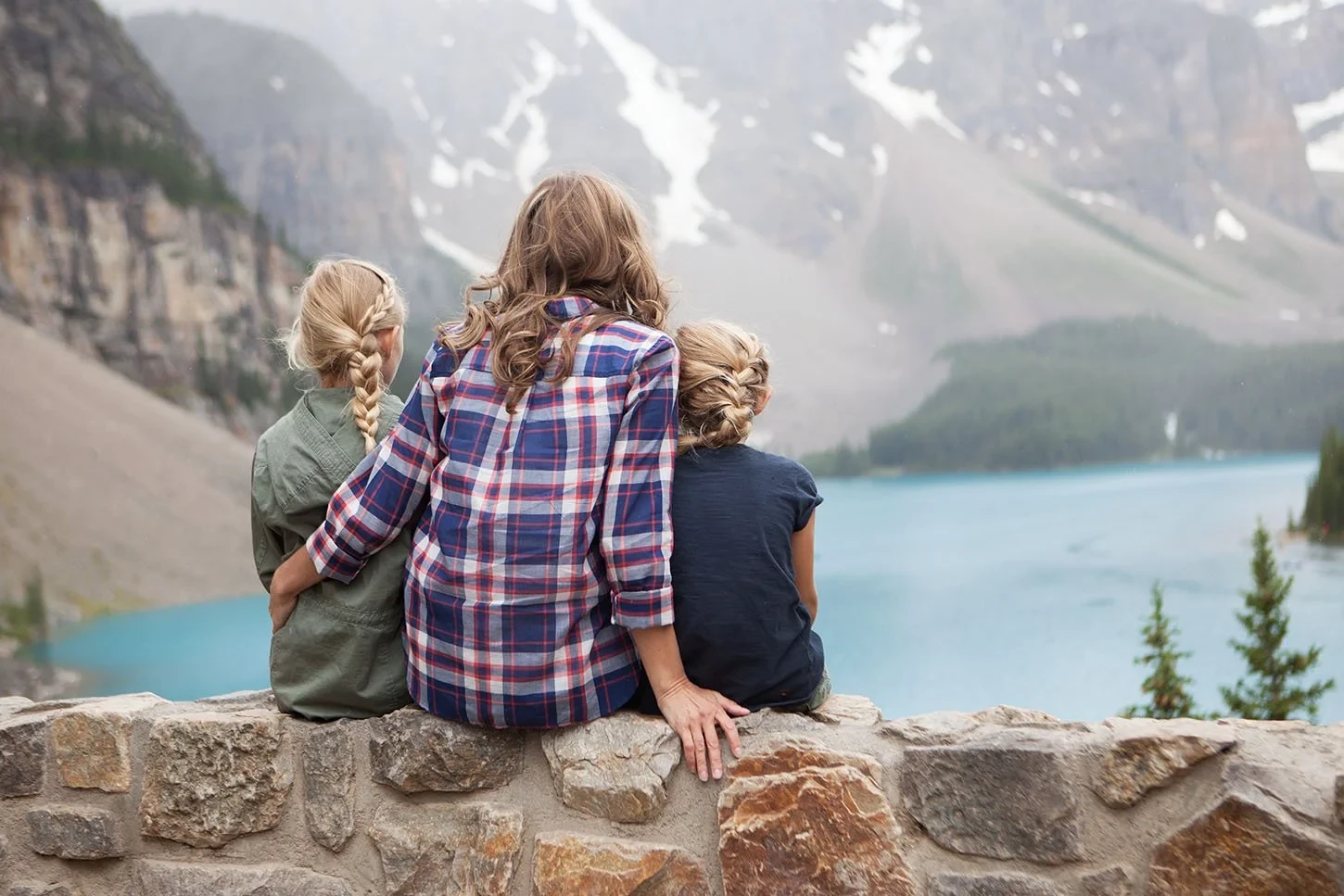 Paysage alpin — enfants sur un mur de pierre contemplant un lac turquoise entouré de montagnes